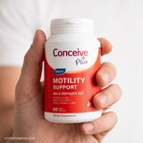 Hand holding a bottle of Conceive Plus Men's Motility Support supplement.